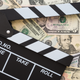 Cinema clapperboard on US dollars banknote bill background